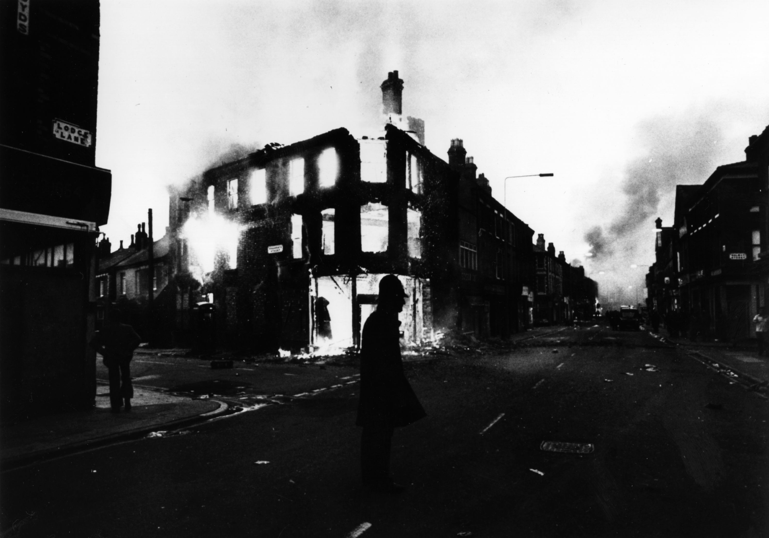 I FLAMMER: En politimann står vakt i Lodge Lane under opptøyene i 1981.